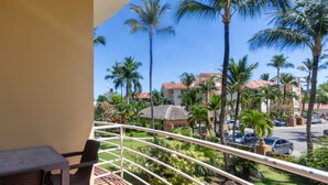 Un balcone con tavolo e sedia che si affaccia su una zona residenziale con palme e case.