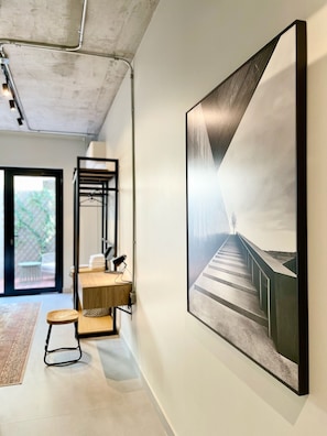 Experience a clean, modern space with a large abstract painting, wooden desk, and metal shelving unit.
