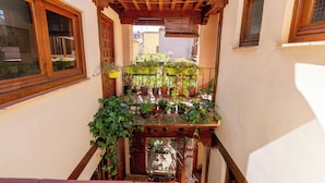 A narrow balcony with wooden railings, potted plants, and a wooden pergola.