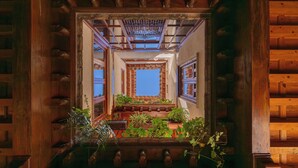 A wooden interior with a central skylight, wooden beams, and potted plants.