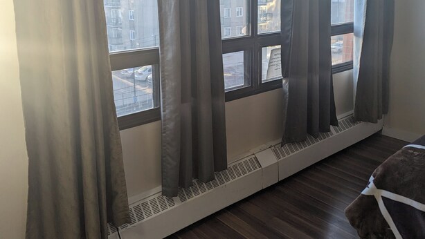 A room with large windows, a radiator, and a wooden floor.