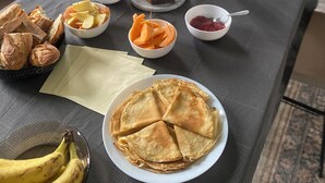 Una tavola imbandita per la colazione, con varie pietanze come pancake, frutta e succo di frutta.