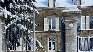 A stone building with a snow-covered entrance and a dog standing in the snow. - In Mayenne, for groups, families and events. (Saint-Cyr-en-Pail)