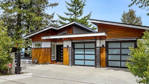Una casa moderna a due piani con garage, ampie finestre e facciata in legno.