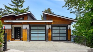 Una casa moderna a due piani con garage, ampie finestre e una parete decorativa in pietra.