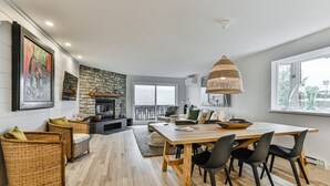 Un vaste espace de vie doté d’une cheminée, d’une table à manger et de sièges confortables.