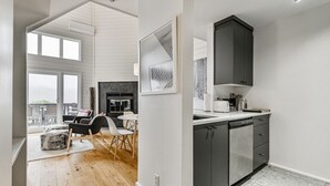 A modern kitchen with dark cabinets, a dishwasher, and a large window.