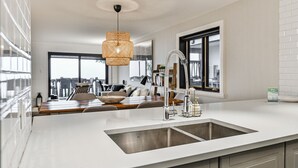 A modern kitchen with a large island, stainless steel appliances, and a hanging light fixture.