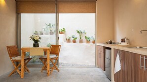 Une cuisine moderne avec un coin repas, de grandes fenêtres et des plantes en pot.