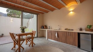 A modern kitchen with wooden cabinets, a stainless steel refrigerator, and a dining area with a table and chairs. - Casa Oma 04: in the heart of Tepoztlán (Tepoztlán)