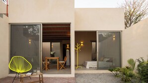 A modern building with a patio area featuring a wooden table, chairs, and a bright yellow chair. - Casa Oma 04: in the heart of Tepoztlán (Tepoztlán)