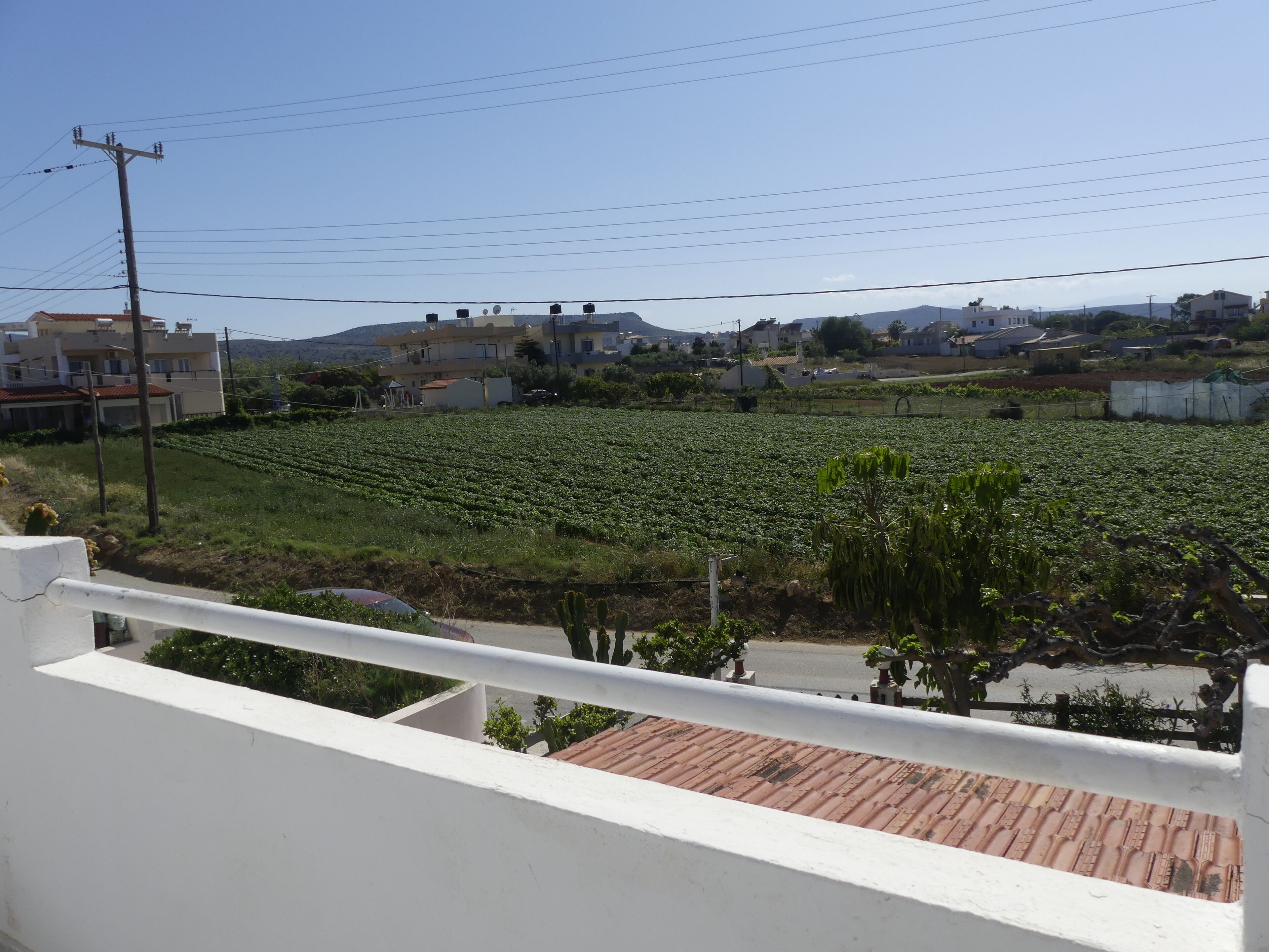 A balcony with a view of a residential area, including houses and a field.