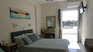 A bedroom with a bed, bedside tables, a dresser, a mirror, and a view of the outside. - AMZ Apartments (Kato Gouves)