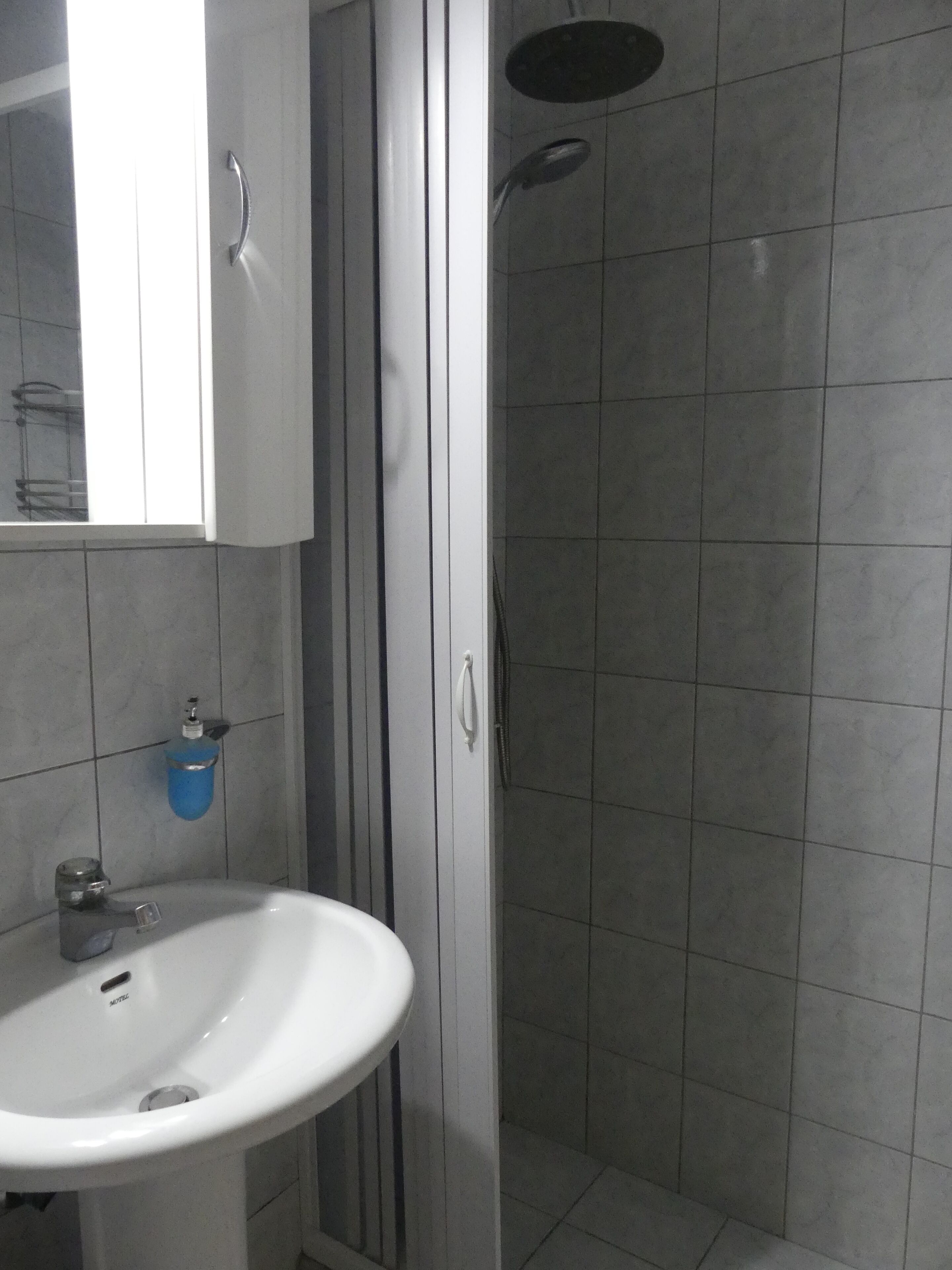A bathroom with a white sink, a mirror, and a shower area.