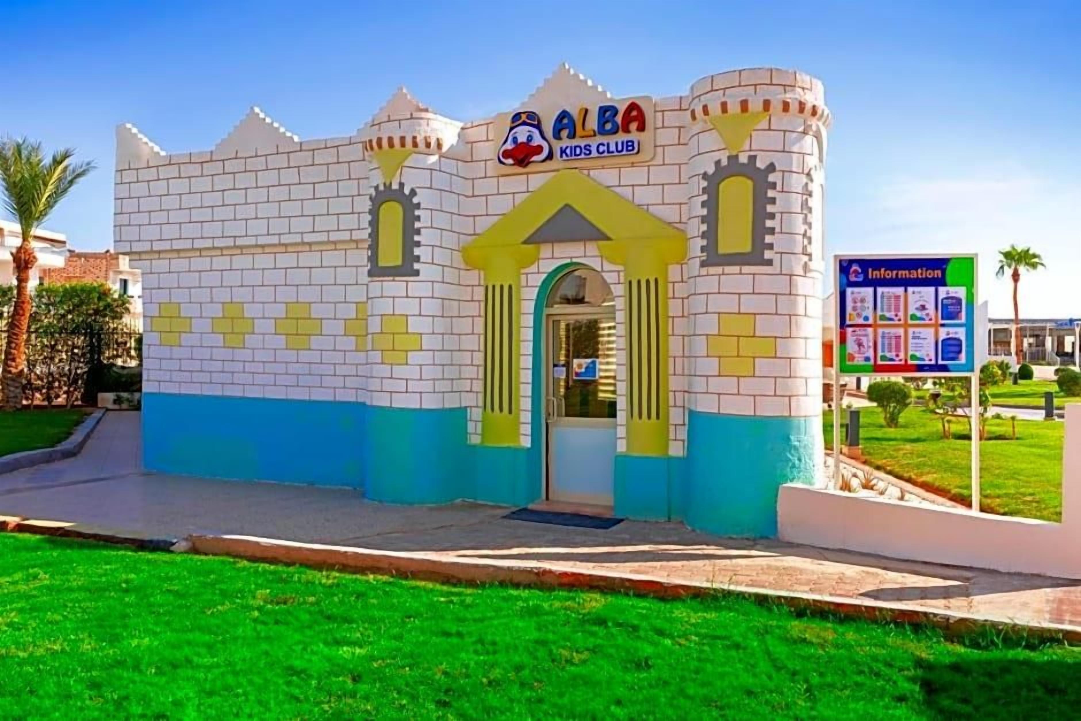 A children's club building with a castle-like facade, a signboard, and a grassy area in front.