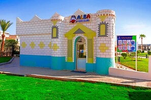 A children's club building with a castle-like facade, a signboard, and a grassy area in front. - Albatros Sharm Resort By Pickalbatros (Sharm El Sheikh)