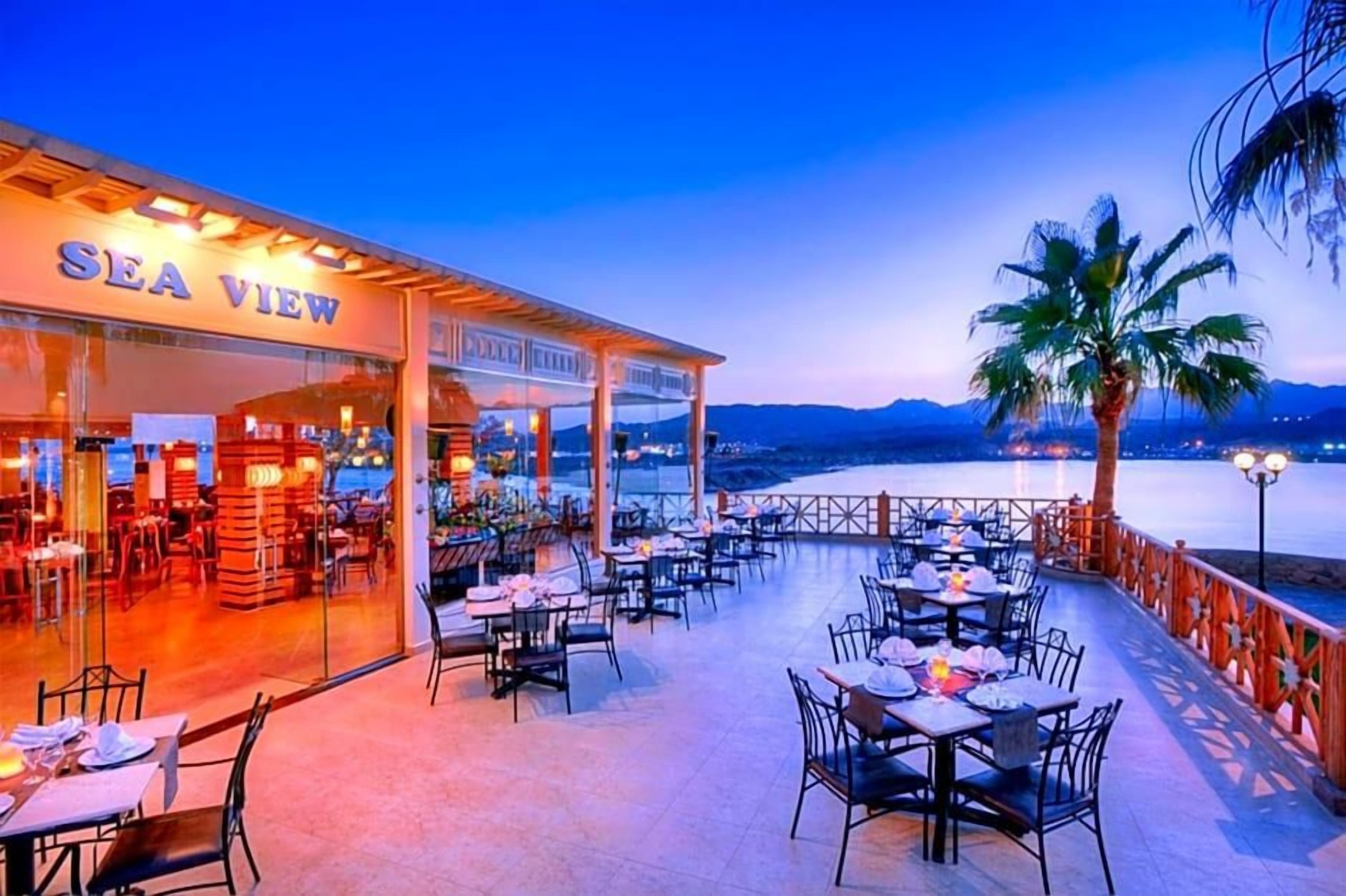 A restaurant named SEA VIEW with outdoor seating overlooking a body of water and mountains.
