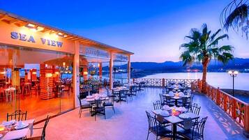 A restaurant named SEA VIEW with outdoor seating overlooking a body of water and mountains.