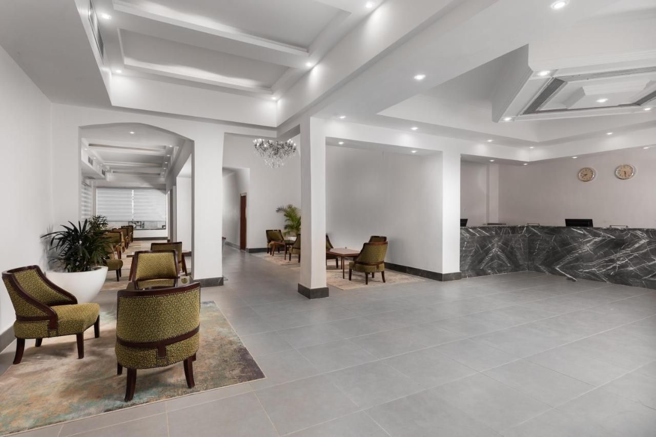 A spacious lobby with a reception desk, seating area, and a chandelier.