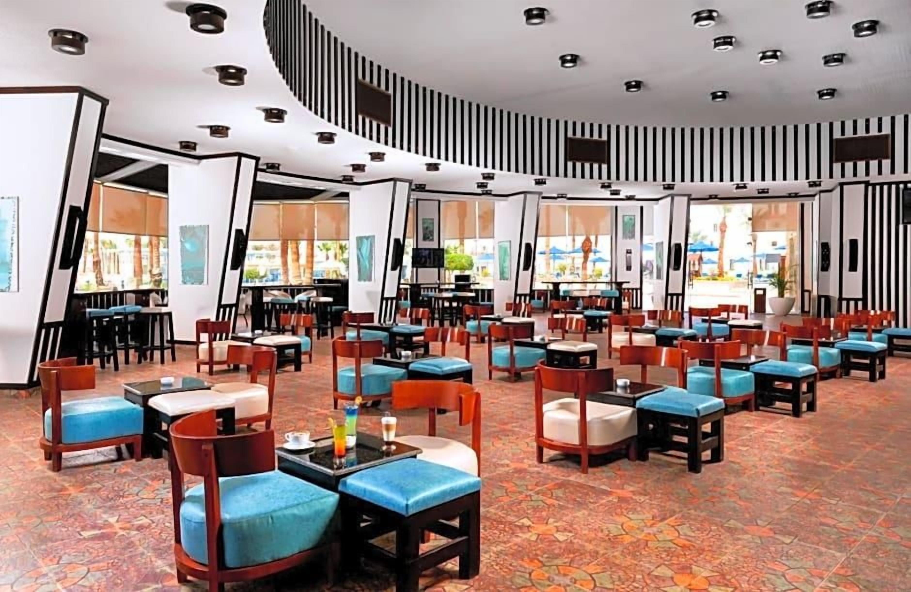 Un hall d’hôtel doté de plusieurs espaces de détente, comprenant des tables et des chaises, et un sol à motifs.