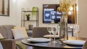 A dining table set with plates, wine glasses, and a vase with flowers. - Beautiful Apartment at Gare de L'est Republique (Paris)