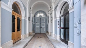 A corridor with a tiled floor, a wooden door, and a glass door with a handle. - Beautiful Apartment at Gare de L'est Republique (Paris)