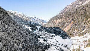 Un valle con montañas nevadas, una población con edificios y un río.