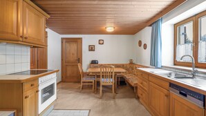 Una cocina con armarios de madera, horno empotrado, mesa de comedor con sillas y ventana con vistas.