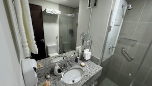 A bathroom with a granite countertop sink, a mirror, a toilet, and a glass shower enclosure. - Comfort & king bed near Riocentro and Olympic Park (Jacarepaguá Rio de Janeiro)