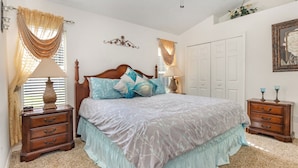 Un dormitorio con cama, dos mesitas de noche, cómoda y ventilador de techo, además de una puerta.