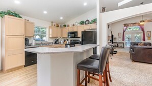 Una cocina moderna con una isla central, armarios de madera y un comedor con sofá y sillas.