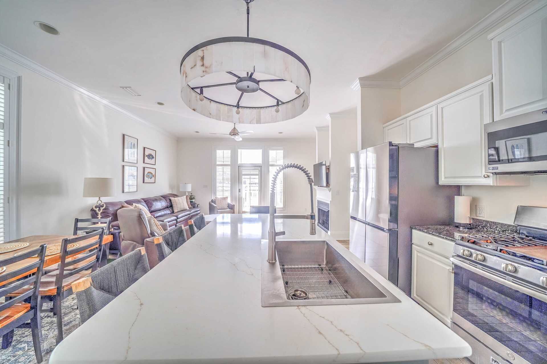 A spacious kitchen with a central island, modern appliances, and a large chandelier.