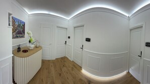 A hallway with white walls, wooden floors, and a reception desk. There are doors labeled "PARICI" and "ROMA".