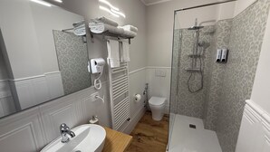 A modern bathroom with a sink, mirror, towel rack, and glass shower enclosure.