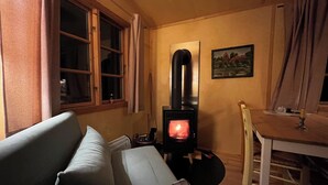 A cozy room with a sofa, a table with a candle, and a wood-burning stove. - Beautiful circus wagon in a secluded location  (Oetzen)