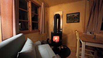 A cozy room with a sofa, a table with a candle, and a wood-burning stove.
