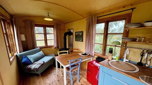 A cozy cabin interior with a wooden dining table, a red kitchen counter, and a blue cabinet. - Beautiful circus wagon in a secluded location  (Oetzen)