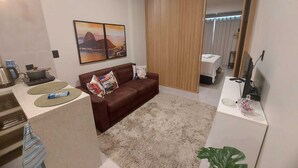 A modern living room with a brown sofa, a coffee table, a TV, and a painting on the wall.