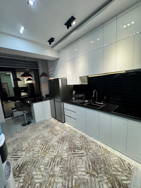 A modern kitchen with sleek cabinetry, a black refrigerator, and a stainless steel sink.
