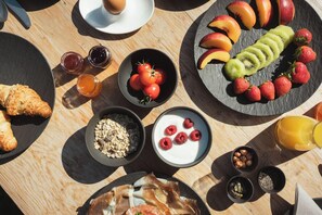 A breakfast setting with various food items and drinks on a wooden table. - Gailerhof Hotel B B Superior (Monguelfo)