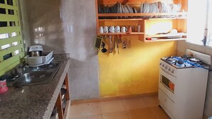 Una cocina compacta con estufa a gas, horno pequeño y una repisa con utensilios de cocina.