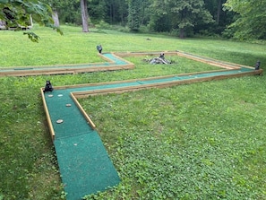 Un parcours de minigolf avec un chemin recouvert d’un tapis vert et bordé de bois.