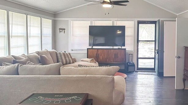 Un salón amplio con un sofá modular grande, un televisor de pantalla plana y un ventilador de techo.