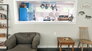 Una sala de estar con un amplio ventanal que da a una cocina.