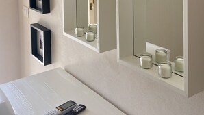 Une salle de bain avec un grand miroir, un meuble-lavabo et une étagère avec des bougies.