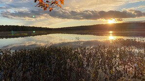Un lago tranquilo con hojas otoñales y un atardecer.