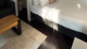 Un dormitorio con cama, una banca, inodoro y zona de ducha.