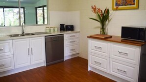 A kitchen with white cabinets, a dishwasher, a microwave, and a wooden countertop.