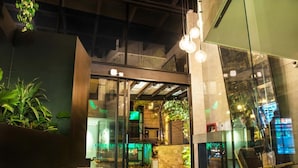 A modern interior with glass doors, indoor plants, and hanging light fixtures.