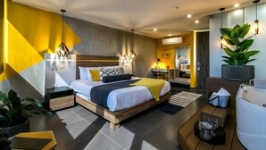Une chambre d’hôtel moderne équipée d’un lit, de tables de chevet, d’un bureau, d’une chaise, d’une plante et d’une baignoire.